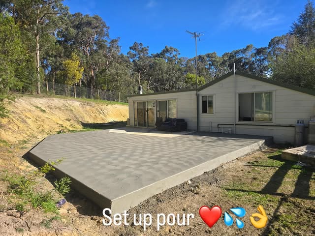 Large outdoor concrete patio slab behind a weatherboard home